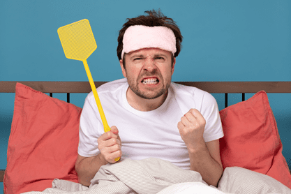 Frustrated man holding flyswatter in bed 
