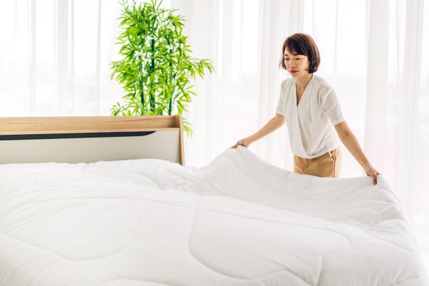A woman changing bed sheets