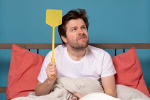 Man in bed with fly swatter