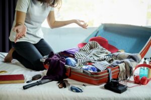 Woman looking at her suitcase with clothes spilling out