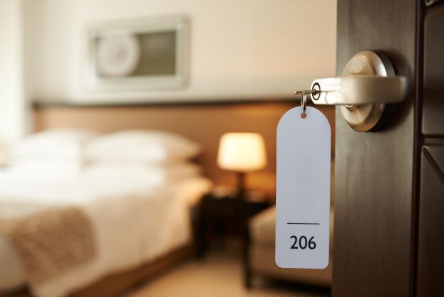 Open hotel room with view of bed and hotel key in door