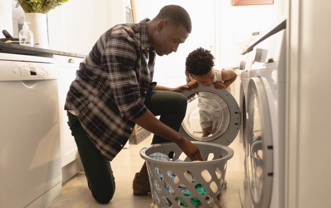Father and child loading clothes and washing machine