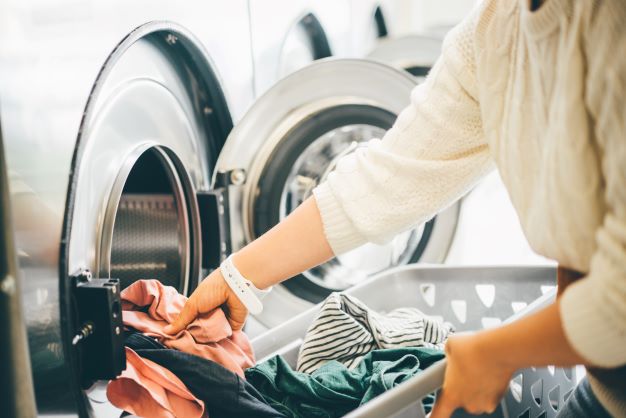 Woman pulling clothes out of dryer at laundromat