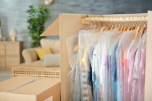 Clothes in plastic hanging in cardboard box ready to move