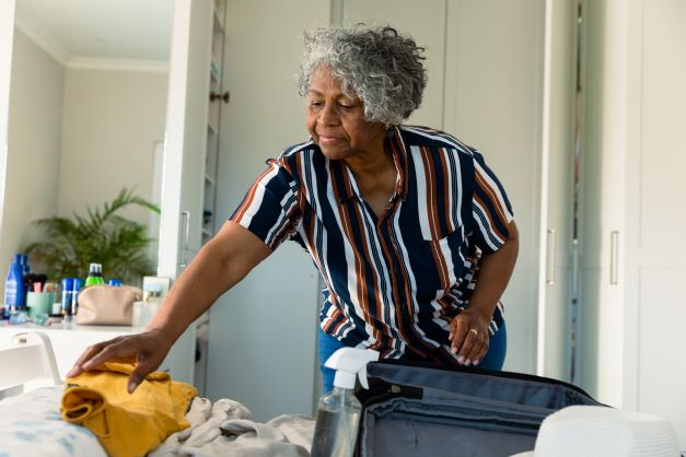 Older woman packing suitcase for travelling