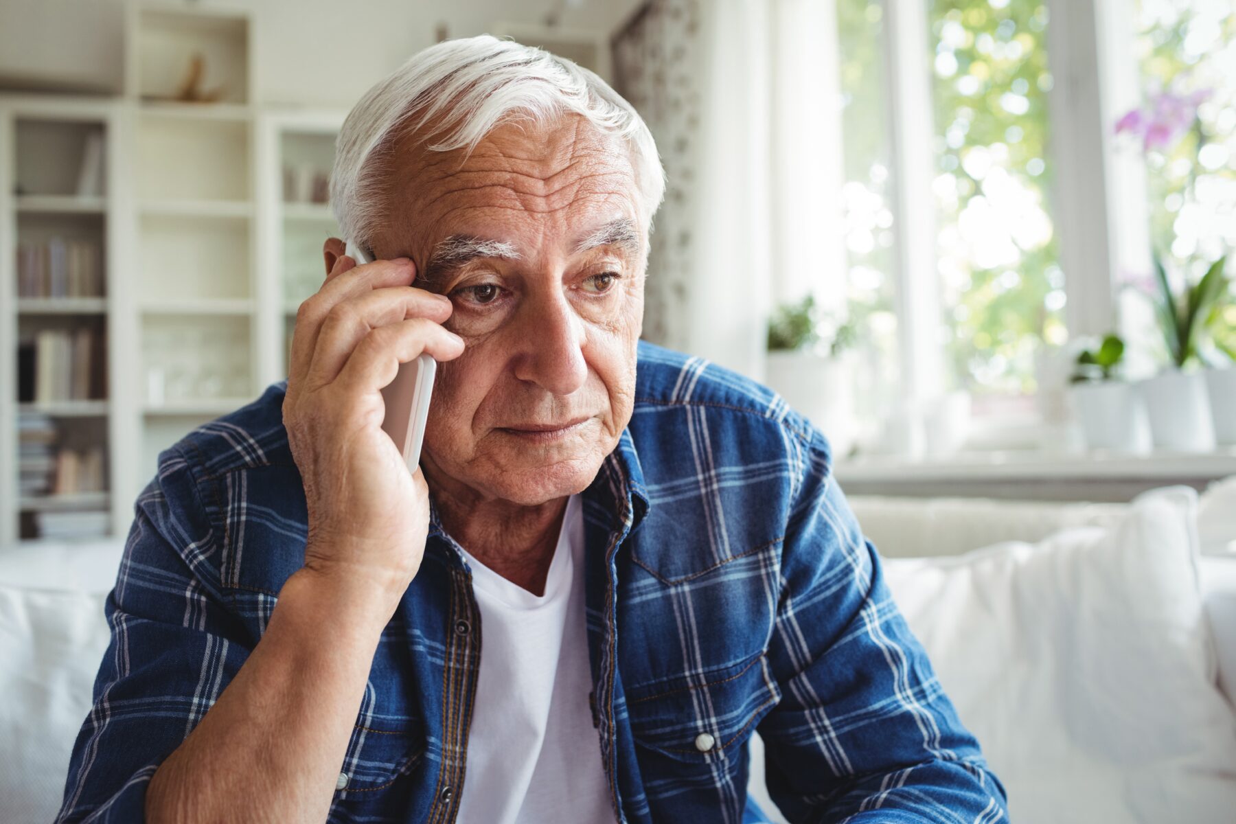 Tensed senior man talking on mobile phone about the early signs of bed bugs